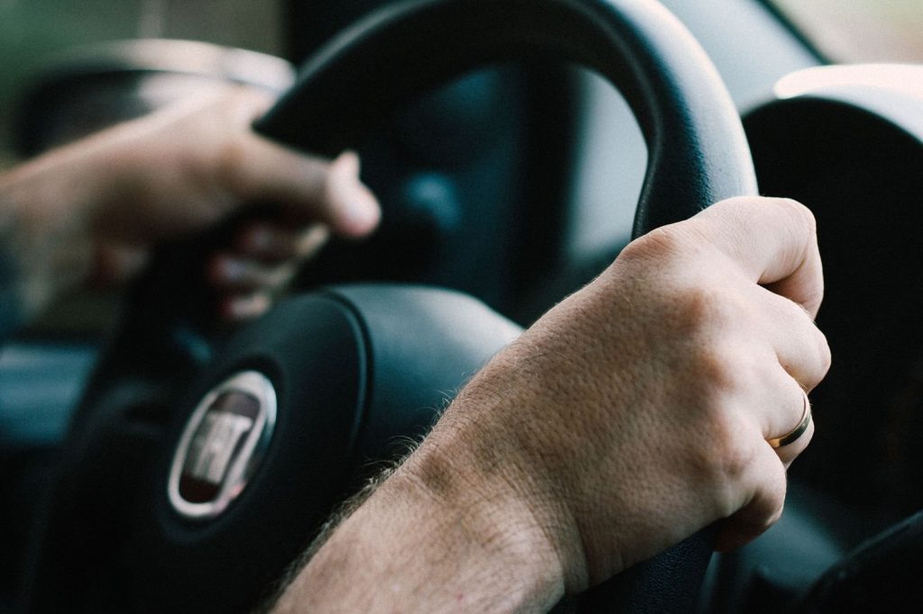 A driver holds the steering wheel inside a car